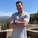 Jordan Jarrett, an Angel Fire, New Mexico real estate agent, standing outdoors with arms crossed