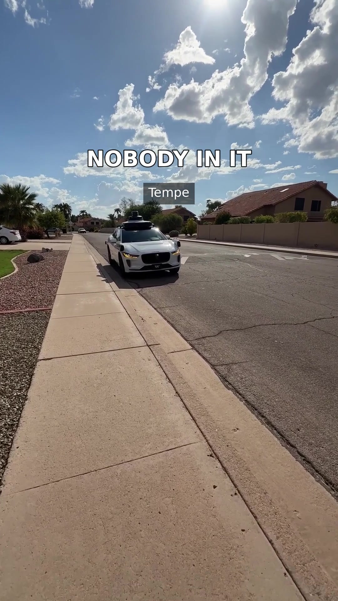 A driverless Waymo vehicle arriving for a first ride on a sunny residential street in Tempe, Arizona