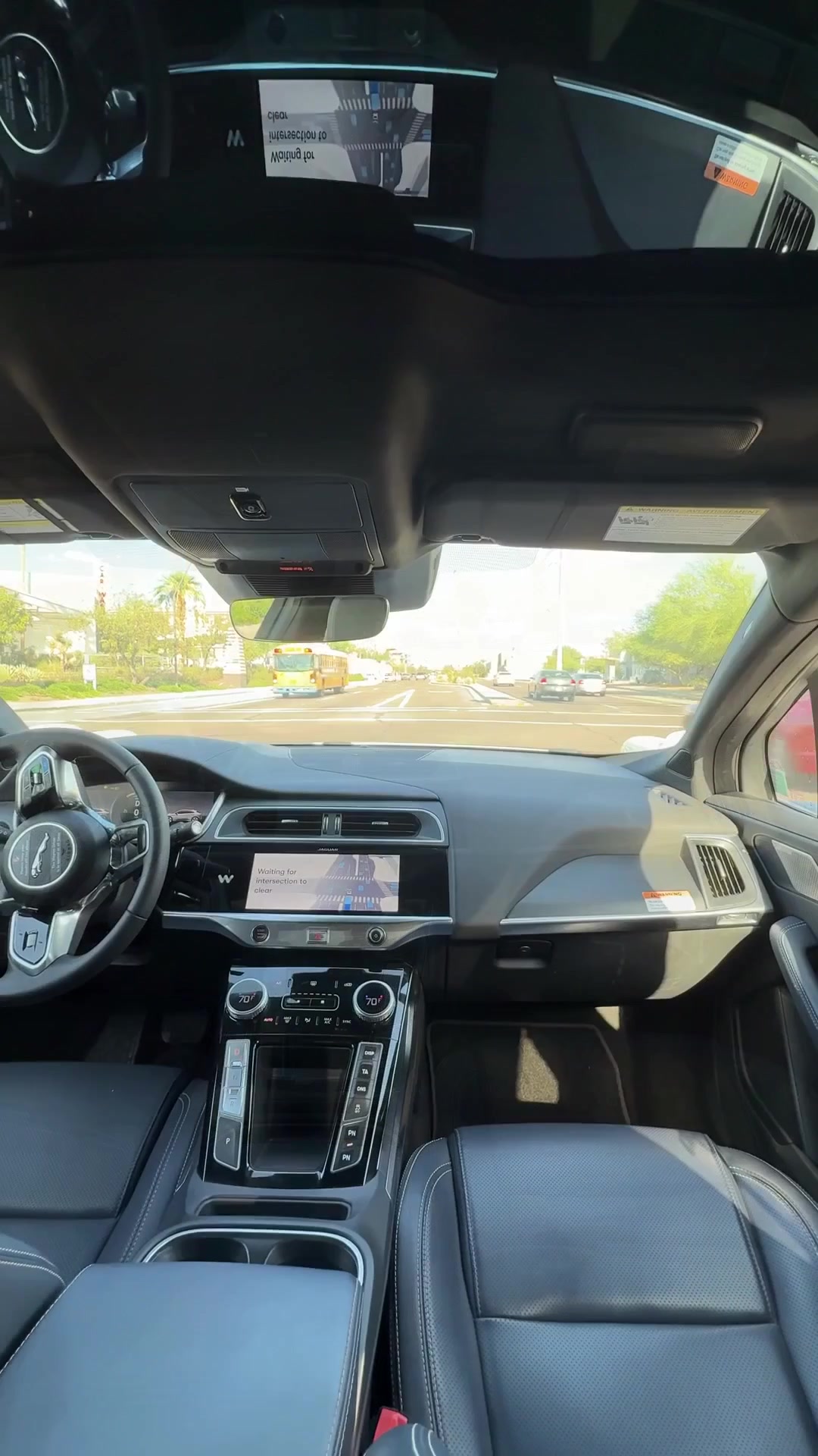 Waymo front cabin with an empty driver seat, steering wheel, and in-car route display during a Tempe first ride